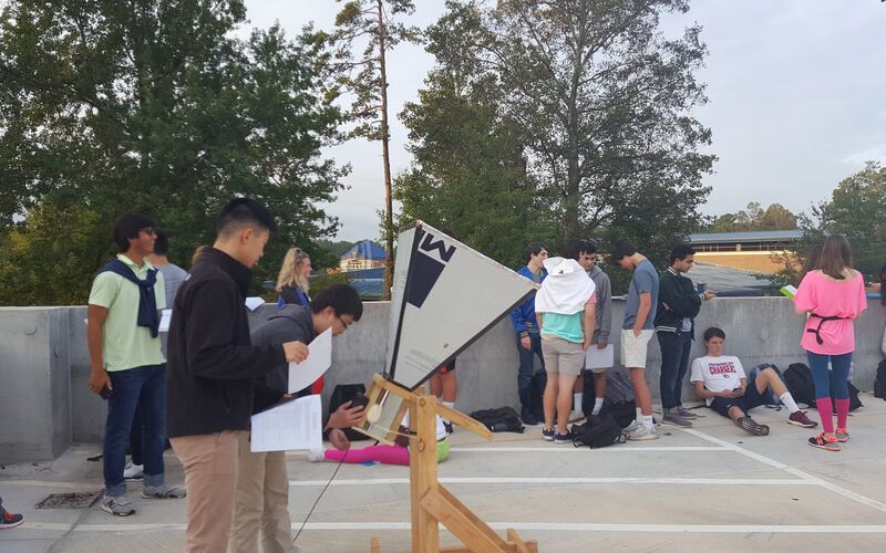 Students setting up a horn telescope in a school parking lot.
